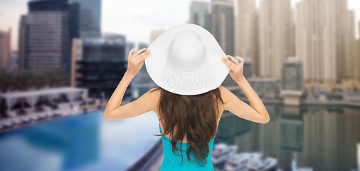 Image showing woman in swimsuit and sun hat from back over city