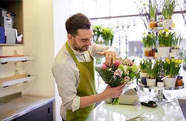 Image showing smiling florist man making bunch at flower shop