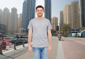 Image showing young man in gray t-shirt and jeans over city 