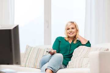 Image showing smiling woman with remote watching tv at home