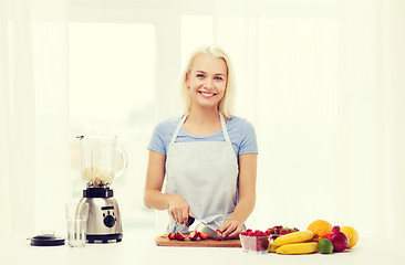 Image showing smiling woman with blender preparing shake at home