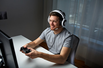 Image showing man in headset playing computer video game at home