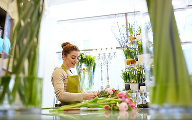 Image showing smiling florist woman making bunch at flower shop