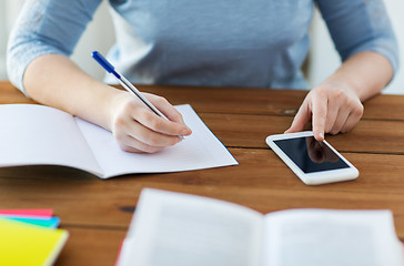 Image showing close up of student with smartphone and notebook