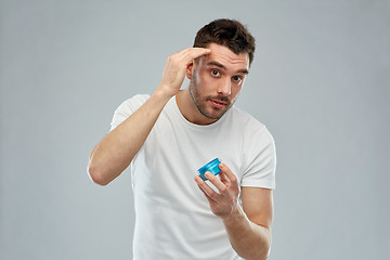 Image showing happy young man styling his hair with wax or gel