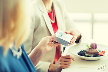 Image showing close up of women giving present at restaurant