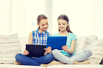 Image showing happy girls with tablet pc sitting on sofa at home