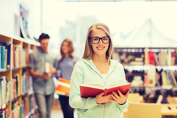 Image showing happy student girl or woman with book in library