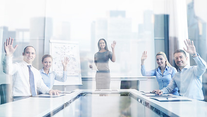 Image showing group of businesspeople waving hands in office