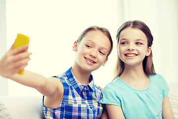 Image showing happy girls with smartphone taking selfie at home