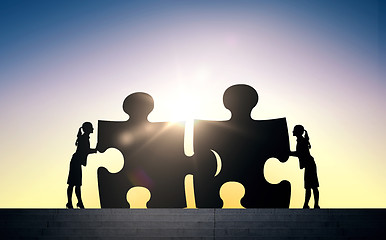 Image showing silhouette of two business women connecting puzzle