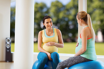 Image showing two happy pregnant women sitting on balls in gym