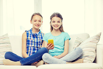 Image showing happy girls with smartphone sitting on sofa