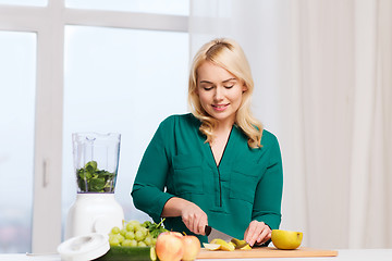 Image showing smiling woman with blender cooking food at home