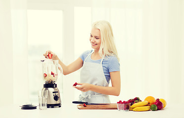 Image showing smiling woman with blender preparing shake at home