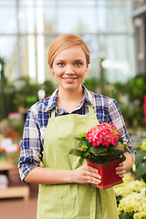 Image showing happy woman holding flowers in greenhouse