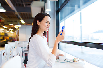 Image showing smiling woman with smartphone and coffee at cafe