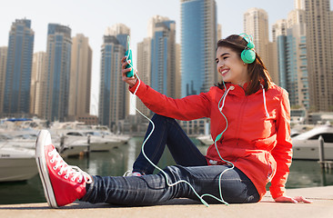 Image showing happy young woman with smartphone and headphones