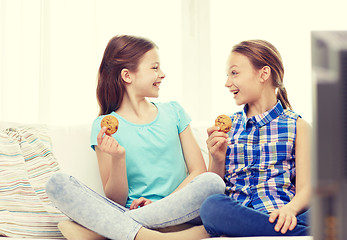Image showing happy girls watching tv and eating cookies at home