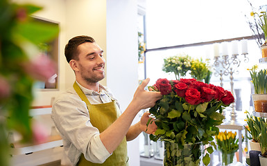 Image showing smiling florist man with roses at flower shop