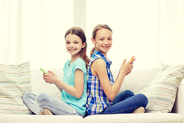 Image showing happy girls with smartphones sitting on sofa