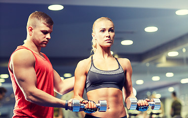 Image showing young couple with dumbbells flexing muscles in gym