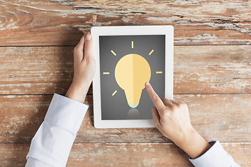 Image showing close up of hands with lighting bulb on tablet pc