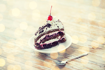 Image showing piece of cherry chocolate cake on wooden table