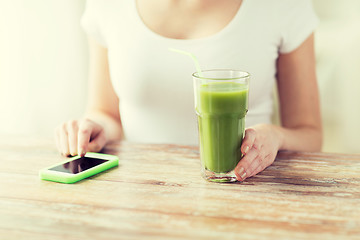 Image showing close up of woman with smartphone and green juice