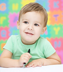 Image showing Little boy is writing on his copybook