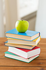 Image showing close up of books and green apple on wooden table