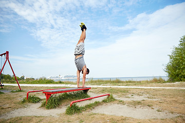 Image showing young man exercising on bench outdoors