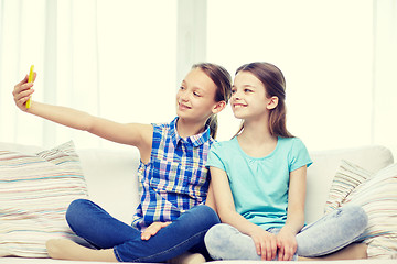 Image showing happy girls with smartphone taking selfie at home