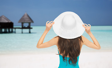 Image showing woman in swimsuit and sun hat from back on beach