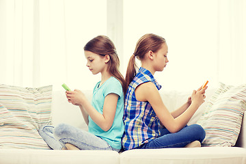 Image showing girls with smartphones sitting on sofa at home