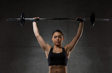 Image showing young woman flexing muscles with barbell in gym