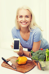 Image showing smiling woman with smartphone cooking vegetables