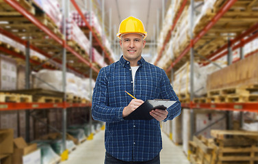 Image showing happy man in helmet with clipboard at warehouse
