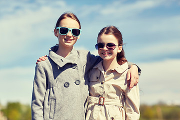 Image showing happy little girls in sunglasses hugging outdoors