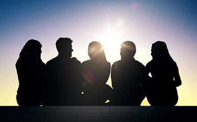 Image showing silhouettes of friends sitting on stairs over sun