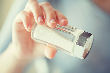 Image showing close up of hand holding white salt cellar