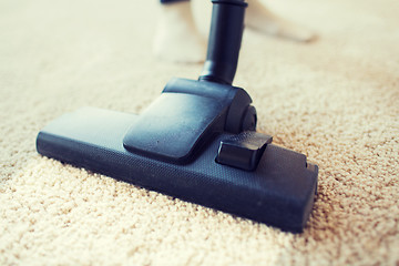 Image showing close up of vacuum cleaner cleaning carpet at home
