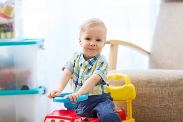 Image showing happy little baby boy driving ride-on car at home