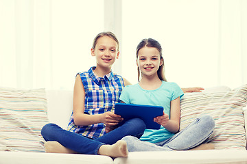 Image showing happy girls with tablet pc sitting on sofa at home