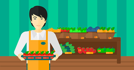 Image showing Supermarket worker with box full of apples.