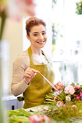 Image showing smiling florist woman making bunch at flower shop