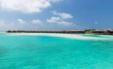 Image showing bungalow huts in sea water on exotic resort beach