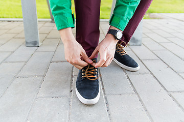 Image showing close up of male hands tying shoe laces on street