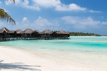 Image showing bungalow huts in sea water on exotic resort beach