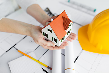 Image showing close up of hands with house model above blueprint